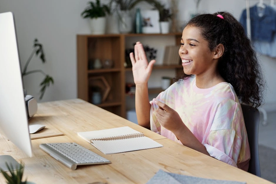 Eine Frau mittleren Alters lernt lächelnd mit einem Tablet auf einem Sofa.